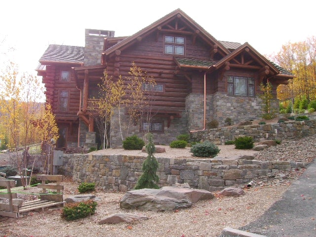 log cabin with grey and gold natural stone veneer on the exterior and landscape walls