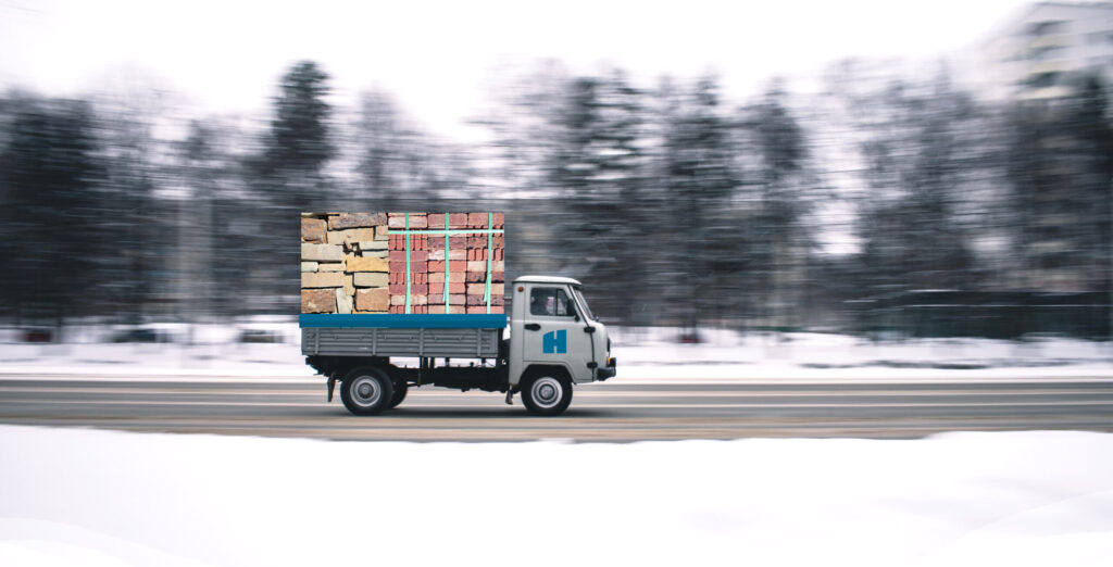 hero image of a delivery truck carrying a load of brick and natural stone down a road with restrictions