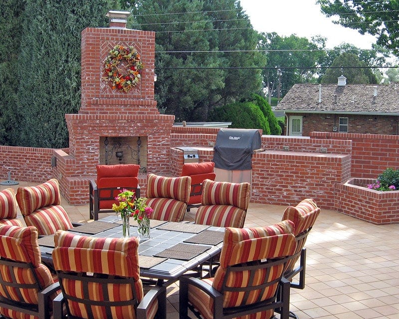 residential patio with red brick fireplace and surrounding landscape walls