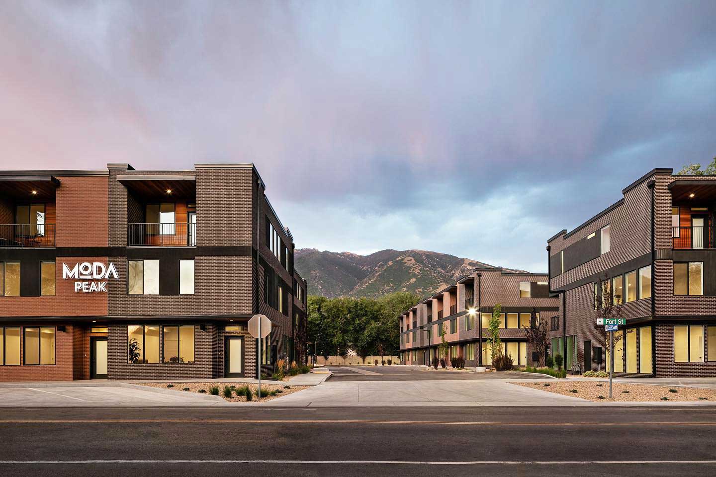 an entry drive into a recently built complex of dark brown brick buildings with heavy black trim