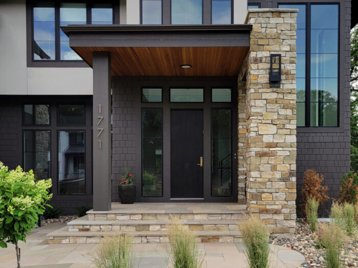 modern home entrance with warm toned stone pillars and natural stone steps
