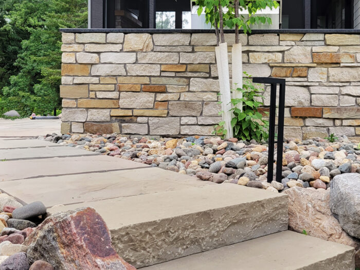 tan and gold veneered landscape wall with natural stone steps and walkway in front