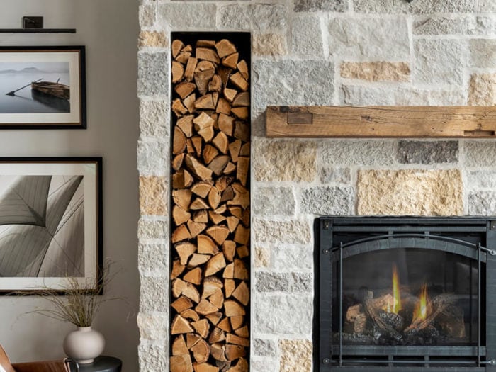residential fireplace featuring light colored natural stone and wood accents