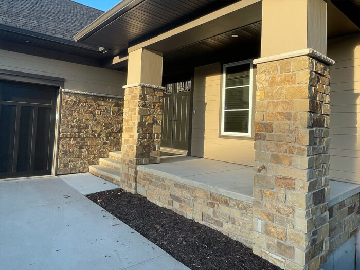 photo of a home's front porch with tan and gold natural stone veneer columns and feature wall