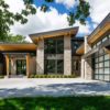 Modern residence with buff colored natural stone, wood grain, and metal cladding on the exterior.