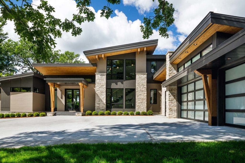 Modern residence with buff colored natural stone, wood grain, and metal cladding on the exterior.