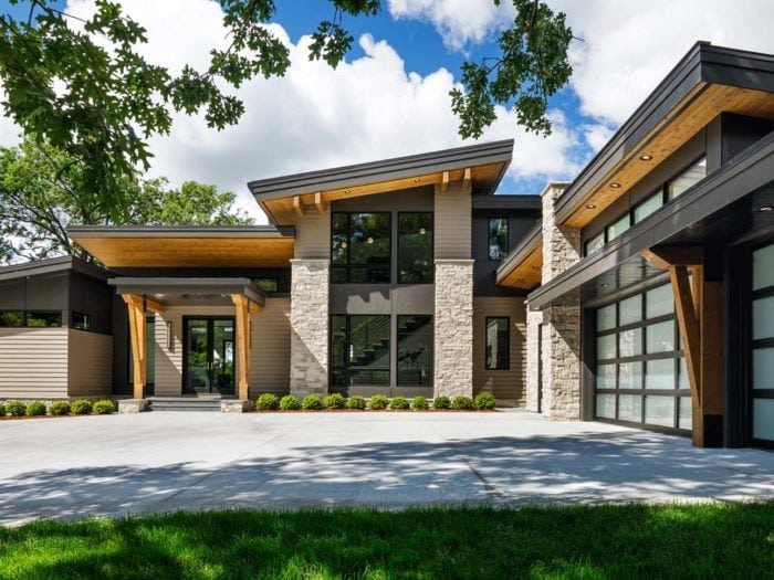 Modern residence with buff colored natural stone, wood grain, and metal cladding on the exterior.