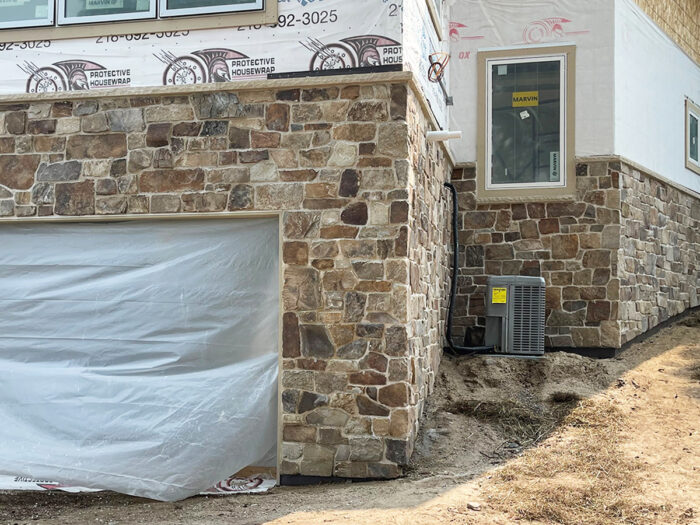 elk mountain natural stone veneer installed around a garage door and wrapping around the side of the house