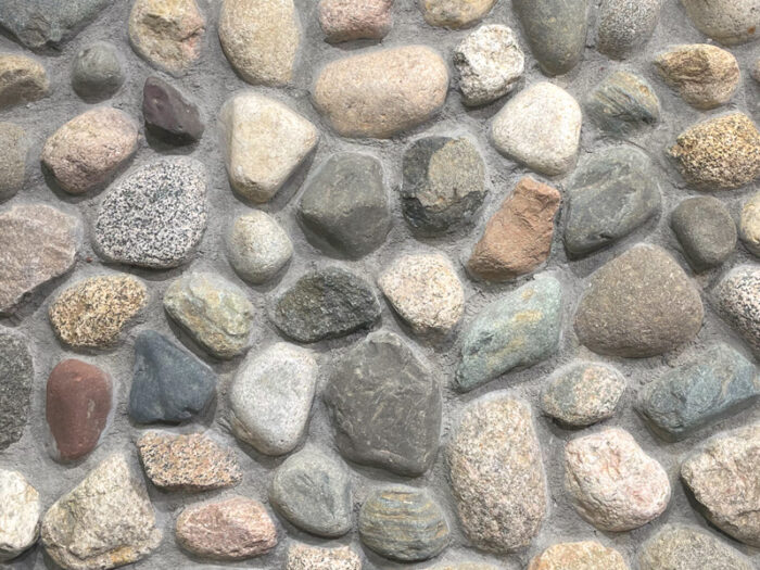 closeup of granite cobble nuggets natural stone veneer display with standard grey mortar