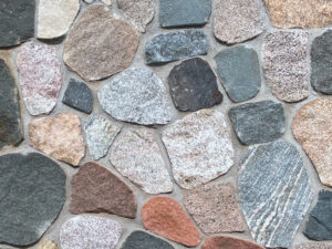 closeup of granite split face cobble natural stone veneer display with standard grey mortar