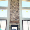 a two story floor to ceiling grey gull cottage natural stone fireplace with large windows on both sides