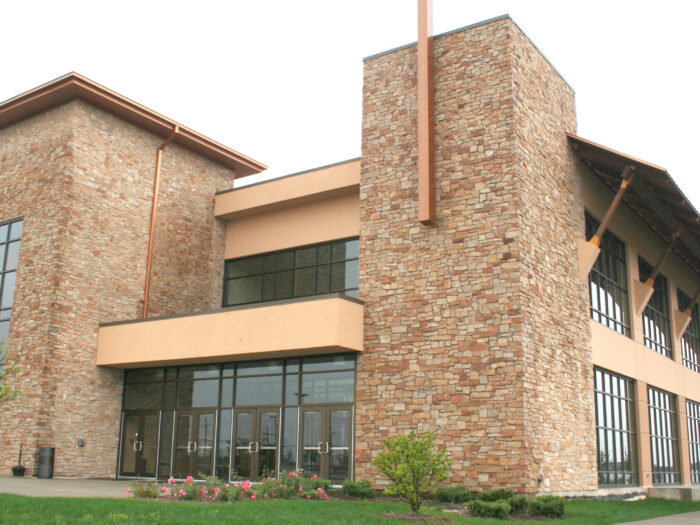 a commercial building exterior featuring highland brown natural stone veneer laid in an ashlar pattern on two large towers that flank both sides of the entry doors