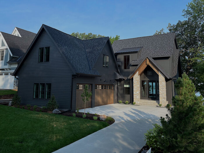 front of home with two garage doors and cream stone pillars surrounding the small front porch and entryway