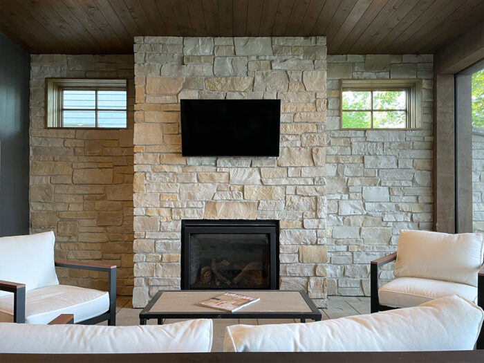 three season porch with wall to wall natural stone and floor to ceiling fireplace