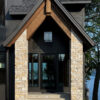 front entryway of a modern lake home with tall, cream stone pillars on both sides of the small front porch