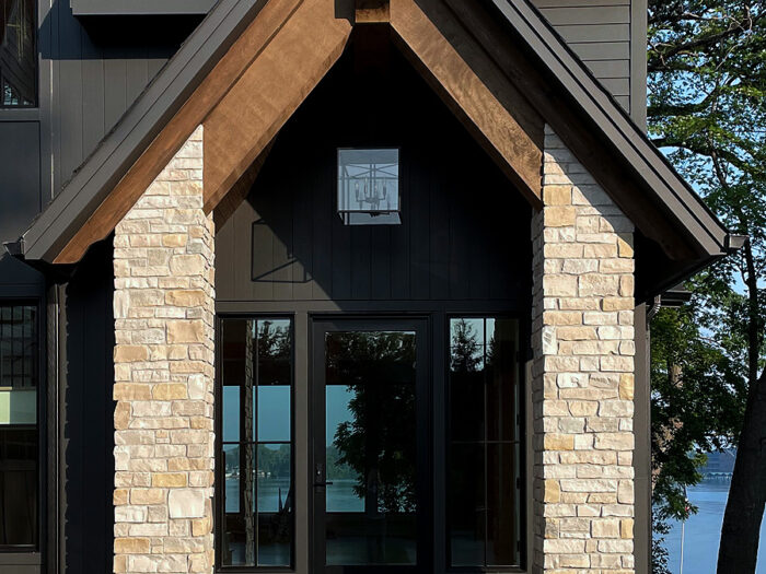 front entryway of a modern lake home with tall, cream stone pillars on both sides of the small front porch