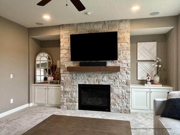 Image of a floor to ceiling fireplace with a ivory and tan colored stone surround with complementary wall colors and interior finishes