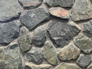 closeup of midwest black web wall natural stone veneer display with standard grey mortar