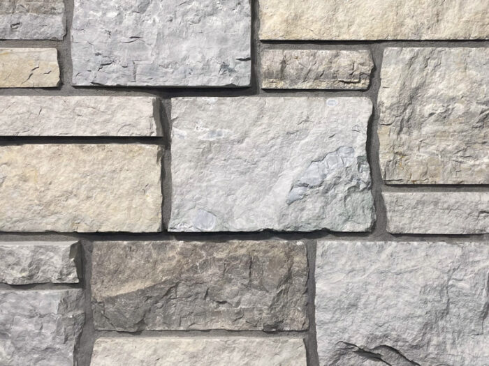 closeup of mountain ridge dimensional natural stone veneer display with standard grey mortar