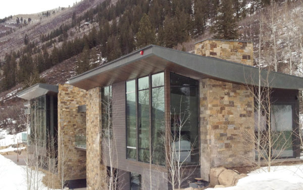 modern mountain home with brown toned stone and large windows