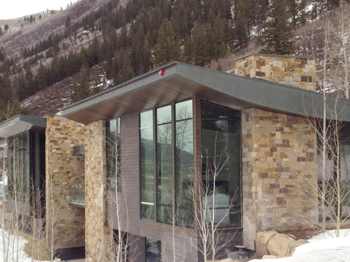 modern mountain home with brown toned stone and large windows