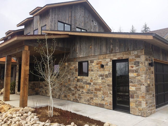 rustic home with warm colored natural stone and barn wood facades