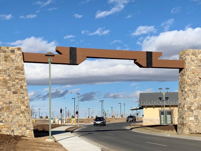 two massive stone pillars on opposite sides of a road with wood beam connecting them above