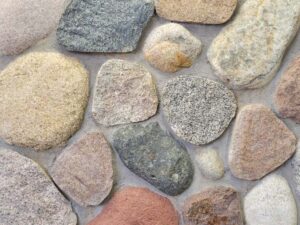 closeup of river blend granite cobble natural stone veneer display with standard grey mortar