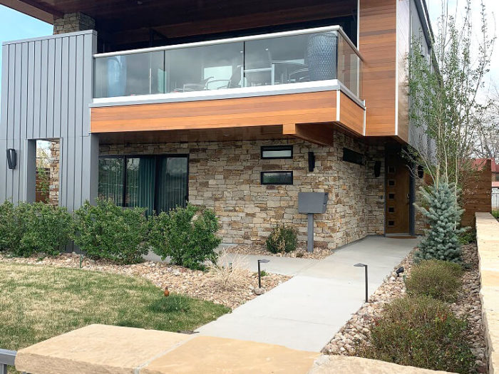 contemporary home with tan colored stone exterior and landscape walls