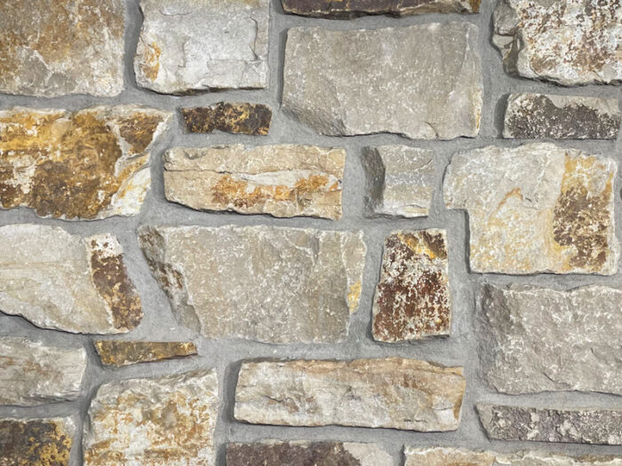 closeup of san miguel tumbled natural stone veneer display with standard grey mortar