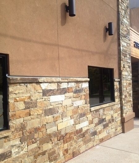 building exterior with brown stucco and brown toned stone wainscot and pillar