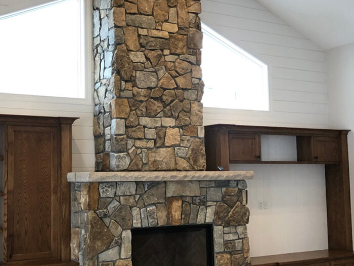 natural stone fireplace extending from floor to ceiling with sherwood forest veneer