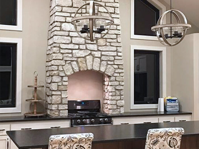 residential kitchen with a tall, counter-to-ceiling fireplace veneered with stone harbor splitface tumbled veneer