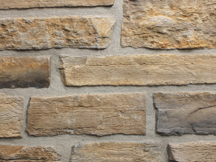closeup of wisconsin weathered edge manufactured stone veneer display with standard grey mortar